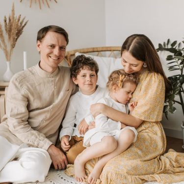 Happy family of four enjoying quality time together in a cozy, plant-filled room.